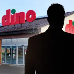Sylwetka mężczyzny w garniturze na tle sklepu Dino.