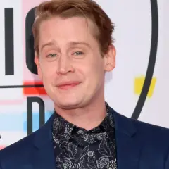 Macaulay Culkin, żyje i ma się dobrze, pozuje na tle napisu "MUSIC AWARDS".