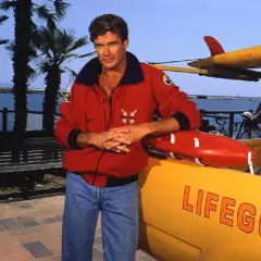 David Hasselhoff, ikona serialu Baywatch Słoneczny Patrol, pozuje przy łodzi ratowniczej.