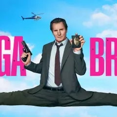 Liam Neeson w filmie "Naga broń" w akcji, z pistoletem i odznaką policyjną. W tle helikopter.