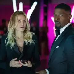 Cameron Diaz i Jamie Foxx znowu w akcji, w eleganckich strojach, na tle neonowych świateł.