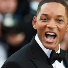 Will Smith w czarnym smokingu z muszką, uśmiecha się szeroko. Ciekawe, ile lat ma Will Smith, patrząc na jego energię!