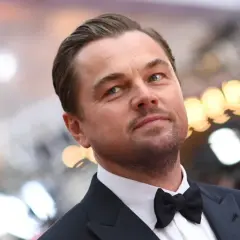 Leonardo DiCaprio w garniturze z muszką, zastanawia się, ile zarabia.