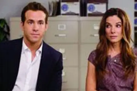Ryan Reynolds i Sandra Bullock, gwiazdy filmu "Narzeczony mimo woli", siedzą obok siebie w biurze.