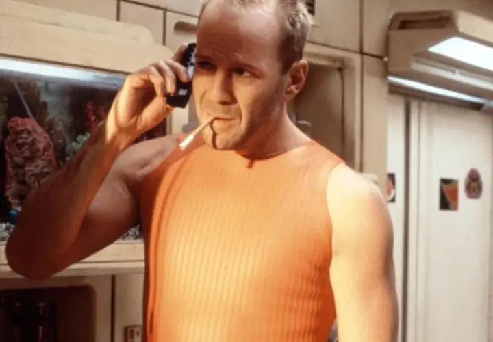 Bruce Willis jako Korben Dallas, jeden z bohaterów "Piątego elementu", rozmawia przez telefon z papierosem w ustach.