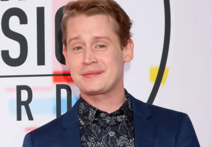 Macaulay Culkin, żyje i ma się dobrze, pozuje na tle napisu "MUSIC AWARDS".