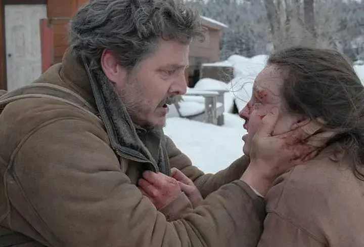 Joel w śnieżnej scenerii, z krwawymi śladami na twarzy, trzyma za podbródek rannego Ellie. To mocna scena, która pokazuje, jak ważna jest obsada w budowaniu napięcia.