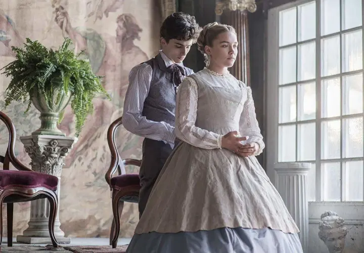 Małe kobietki obsada: Timothée Chalamet i Florence Pugh w strojach z epoki, w eleganckim wnętrzu.