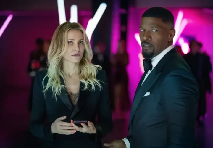 Cameron Diaz i Jamie Foxx znowu w akcji, w eleganckich strojach, na tle neonowych świateł.