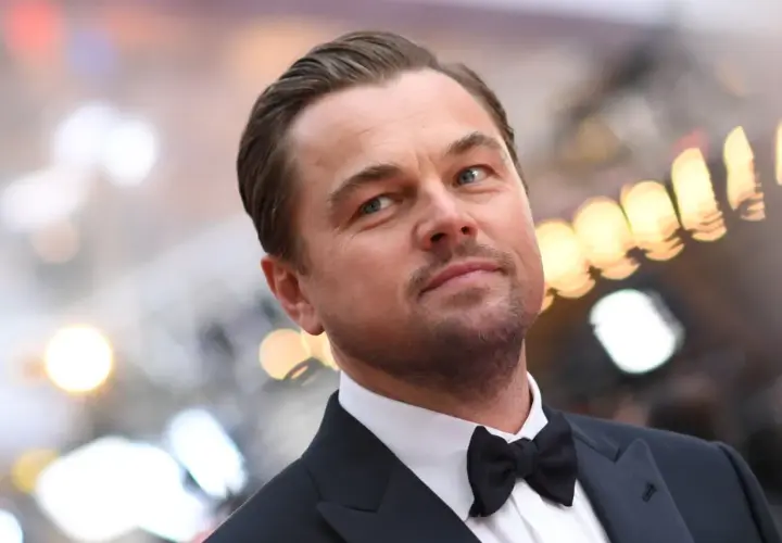 Leonardo DiCaprio w garniturze z muszką, zastanawia się, ile zarabia.