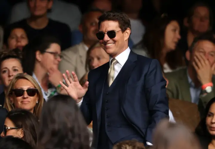 Tom Cruise w garniturze, machający do fanów. Ciekawe, ile zarabia Tom Cruise za takie wystąpienia.