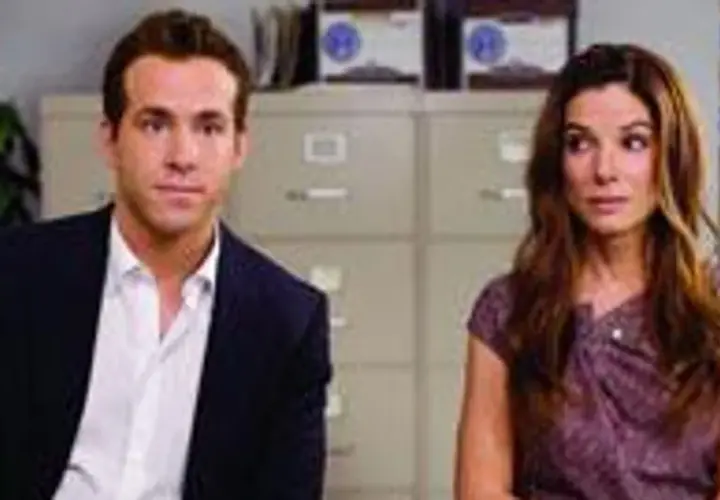 Ryan Reynolds i Sandra Bullock, gwiazdy filmu "Narzeczony mimo woli", siedzą obok siebie w biurze.