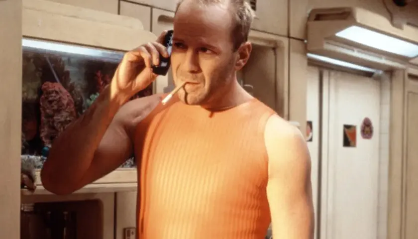 Bruce Willis jako Korben Dallas, jeden z bohaterów "Piątego elementu", rozmawia przez telefon z papierosem w ustach.
