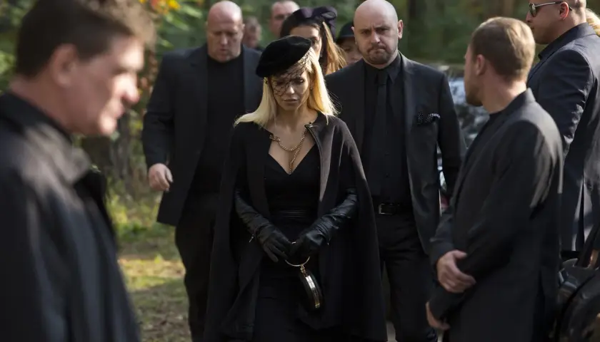 Kobieta w czerni, otoczona ochroniarzami, idzie na pogrzeb. Scena z filmu "Pitbull. Ostatni pies", obsada w żałobie.