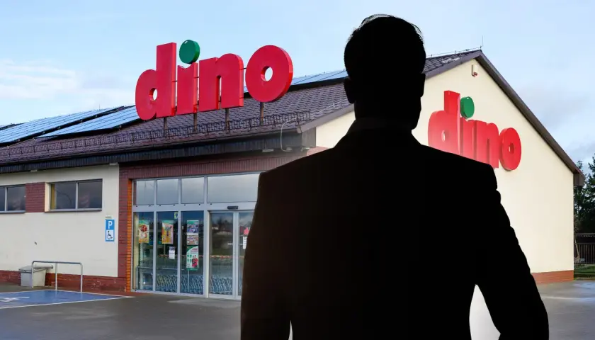 Sylwetka mężczyzny w garniturze na tle sklepu Dino.