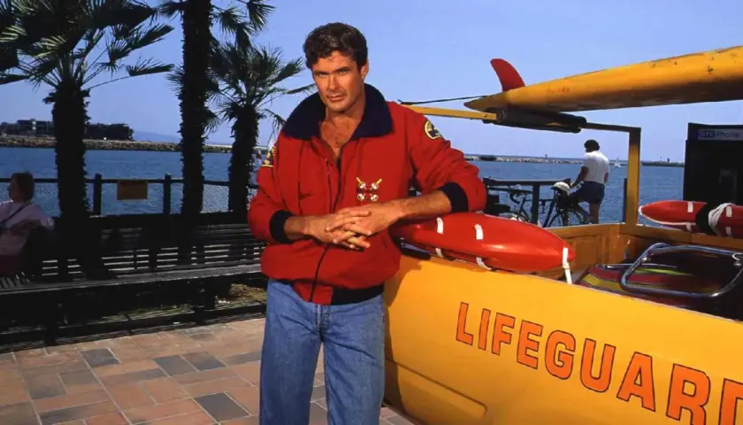 David Hasselhoff, ikona serialu Baywatch Słoneczny Patrol, pozuje przy łodzi ratowniczej.