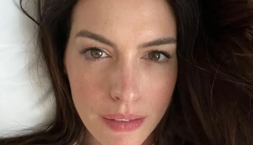 Zbliżenie na twarz Anne Hathaway. Aktorka ma brązowe oczy i ciemne włosy. Wiele osób zastanawia się, ile lat ma Anne Hathaway, ale na tym zdjęciu wygląda młodo i promiennie.