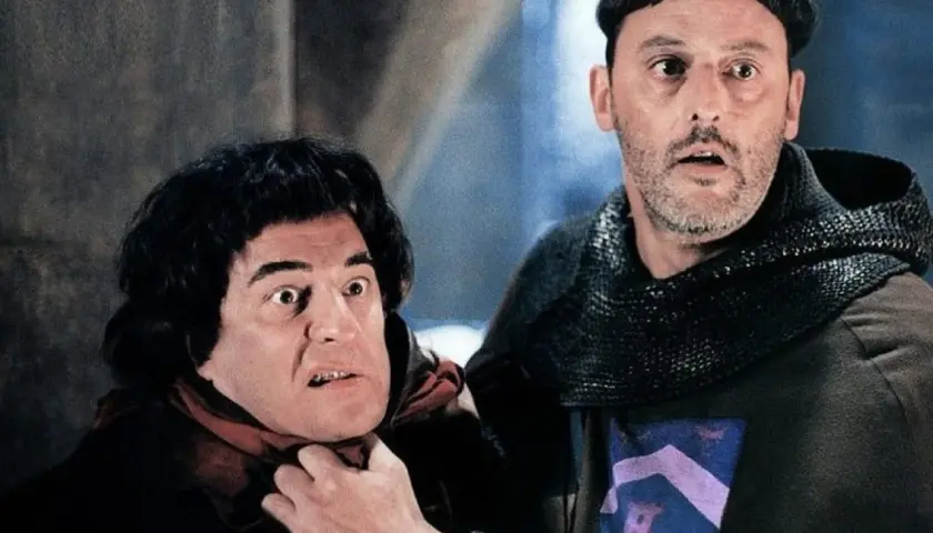 Goście, goście! Obsada filmu w średniowiecznych strojach, jeden z nich groźnie patrzy, drugi ma rękę na jego szyi.