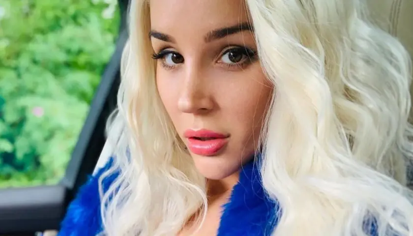 Blondynka w niebieskim futrze, zmysłowe spojrzenie. Ile lat ma sexmasterka? Trudno zgadnąć, wygląda młodo i pięknie.