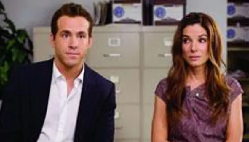 Ryan Reynolds i Sandra Bullock, gwiazdy filmu "Narzeczony mimo woli", siedzą obok siebie w biurze.