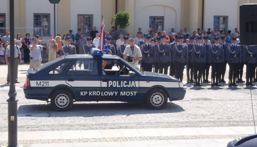 U pana Boga w ogródku obsada: policjanci w mundurach stoją w szeregu obok radiowozu.