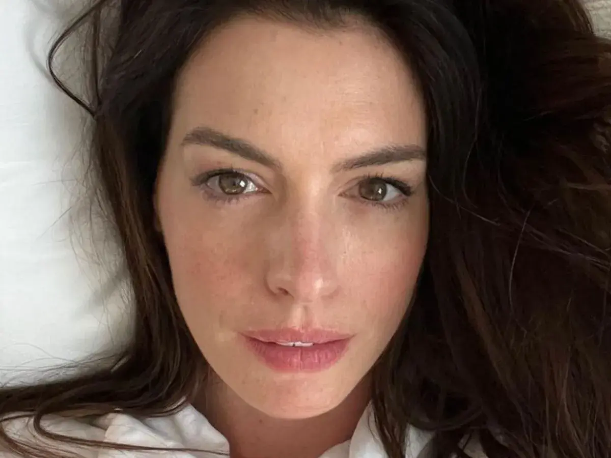 Zbliżenie na twarz Anne Hathaway. Aktorka ma brązowe oczy i ciemne włosy. Wiele osób zastanawia się, ile lat ma Anne Hathaway, ale na tym zdjęciu wygląda młodo i promiennie.