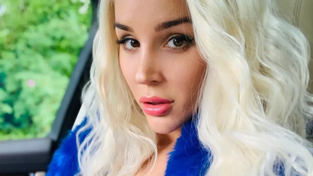 Blondynka w niebieskim futrze, zmysłowe spojrzenie. Ile lat ma sexmasterka? Trudno zgadnąć, wygląda młodo i pięknie.