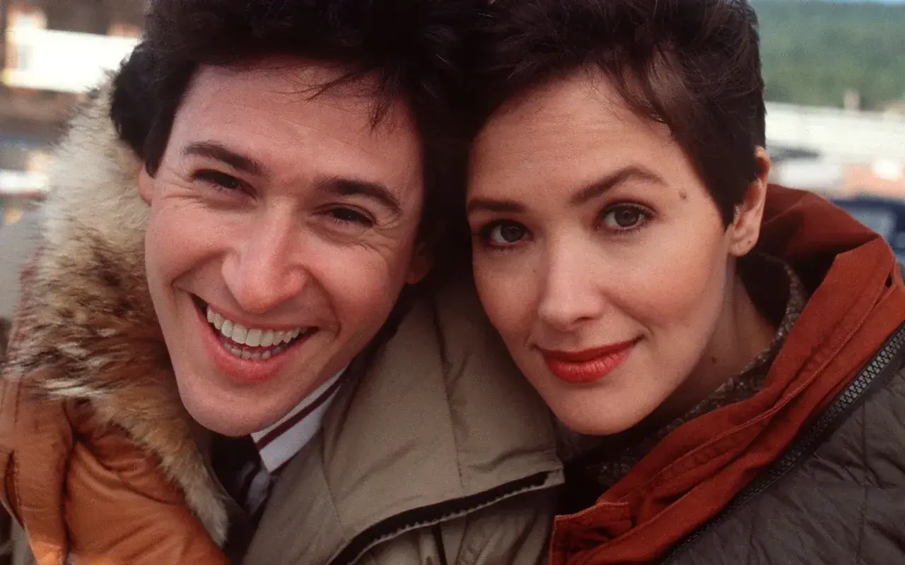 Uśmiechnięci John Cusack i Annette Bening, główni bohaterowie filmu "Przystanek Alaska", w zimowych kurtkach.