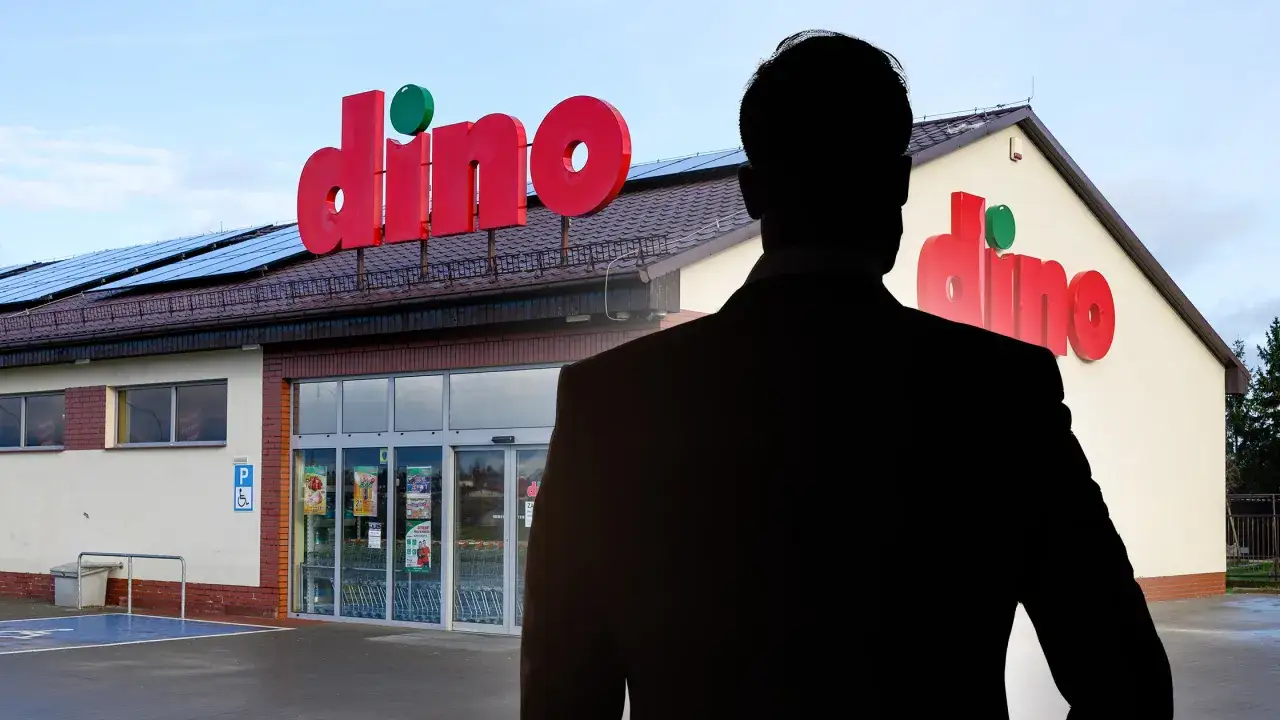 Sylwetka mężczyzny w garniturze na tle sklepu Dino z dużym czerwonym logo.