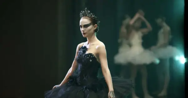 Natalie Portman jako Czarny Łabędź w koronie i czarnej tutu, z innymi tancerkami w tle.